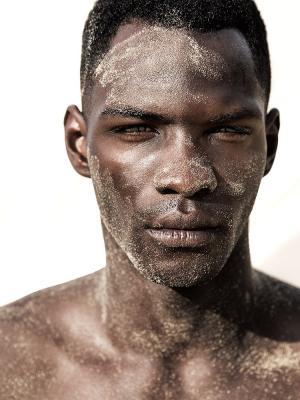 male model dunkelhäutig mit Sand im Gesicht am Strand