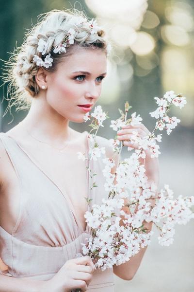 romanic braids, wundervolle Gegenlichtaufnahme, blondes Modell mit dutch breit und Kirschblüten als Haarschmuck, Make up in frischen apricot rosé tönen