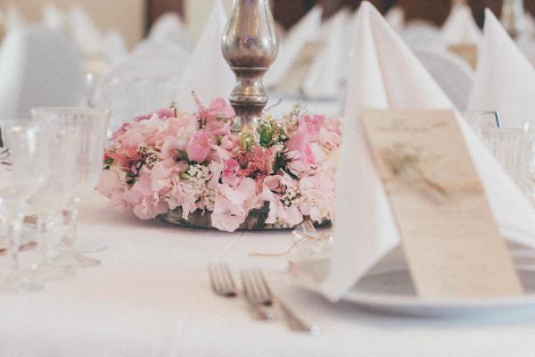 Blumendekoration für Hochzeiten nebst Hochzeitsgedeck. Zarte Farben, antike Kerzenständer und Kristallgläser machen den Vintage look aus.