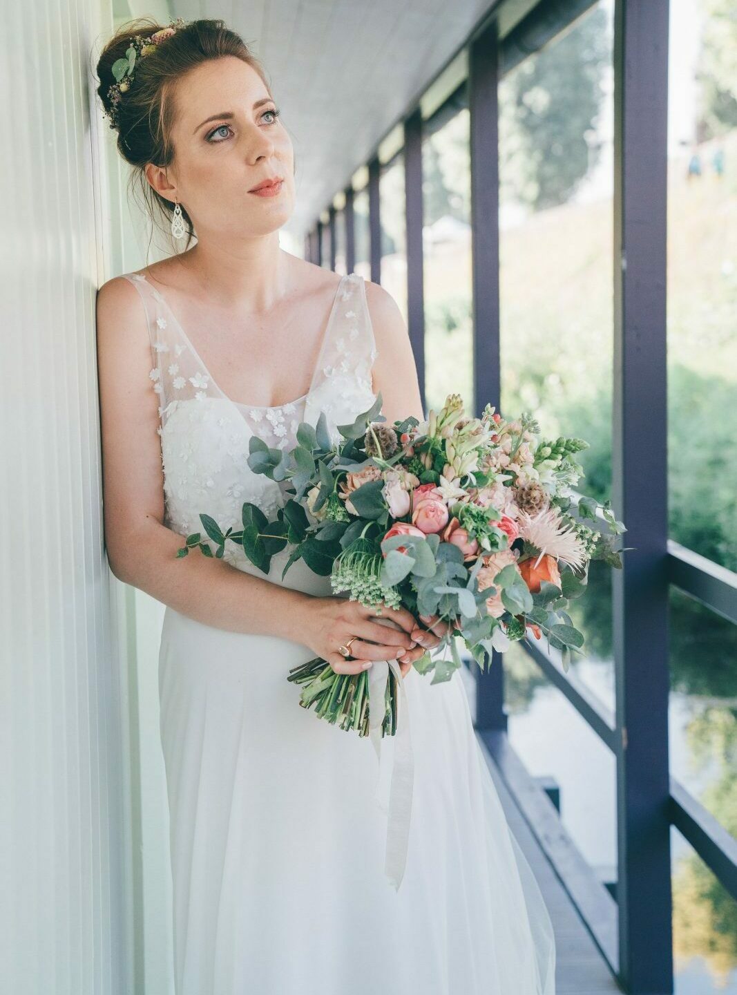 Loose Wedding Bun, verträumtes Brautfoto, die Brautfrisur ist ein hoher, lockerer Dutt, und den einzelne Blüten gesteckt sind